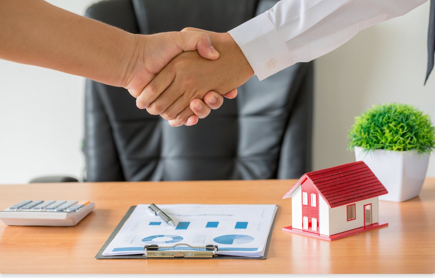A property consultation with a handshake and a model home